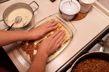 Preparing lasagna in a home kitchen. Cooking homemade meals for the household.