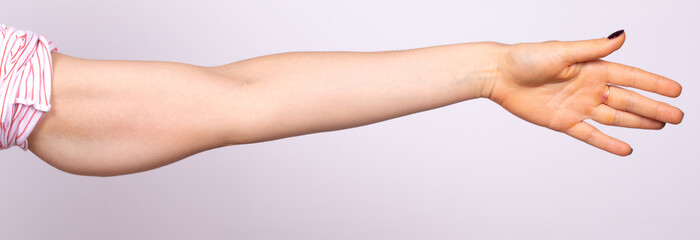 A close up view on the arm of a young woman, isolated against a white background. She holds arm out...