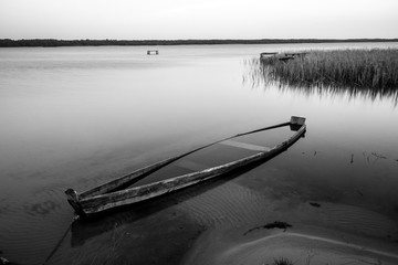 Naklejka premium A canoe on the shore of the lake. A moody landscape. Liutsymer Lake. Polesie. Ukraine
