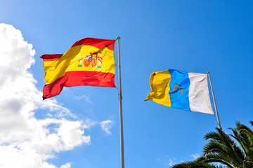 Spanish and Canary Flags blowing in wind on a clouded sky background.