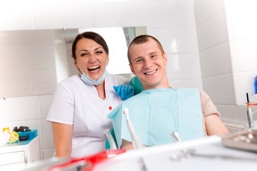 Fototapeta premium The dentist and her happy patient look at the camera and smile. Reception at the dentist, healthy teeth, happy patient, beautiful teeth.