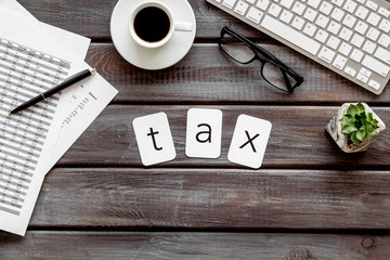Tax copy on accountant work place with keyboard, coffee and glass on wooden desk background top view