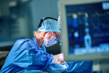 A surgeon's team in uniform performs an operation on a patient at a cardiac surgery clinic. Modern...