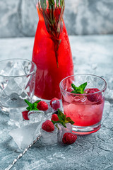 Raspberry cocktail, fizz, lemonade, ice tea with fresh mint on blue wooden background. Close up.