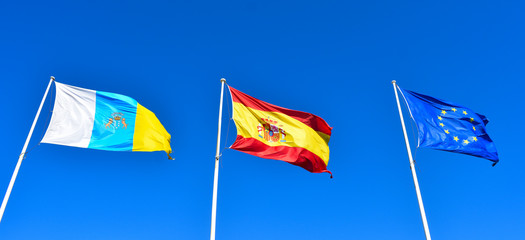 Canary, Spain and EU Flags on a blue sky