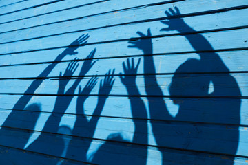 Shadow silhouette of happy young people having fun in Summer on blue wood background, copy space