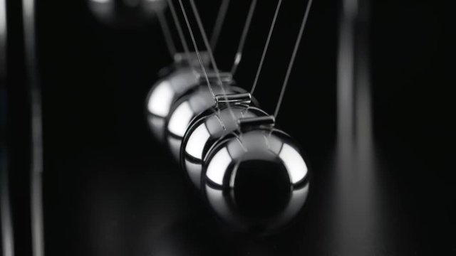 The chrome balls of a Newton&rsquo;s Cradle colliding in slow motion