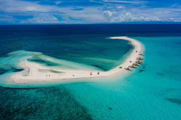 Aerial drone view of a beautiful white sandbar surrounded by coral reef near a tropical island...