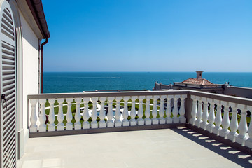 Balcony terrace with white balustrade and gray railing of the second floor of the building...