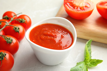 Composition with bowl of tomato sauce on light table