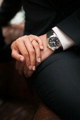 Concept of wrist watch advertising. Close up of holding hands. Elegant man in a black suit and Rich woman in black dress. Young  Fashion stylish man and woman in loft design interior. - 276024966