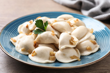 Plate of tasty cooked dumplings on wooden table, closeup