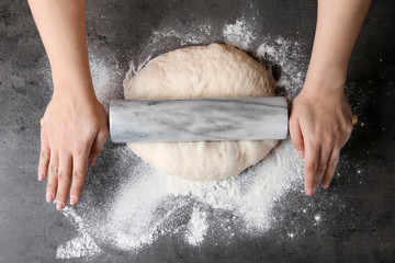 Female baker preparing bread dough at grey table, top view