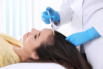 Young woman with hair loss problem receiving injection in salon