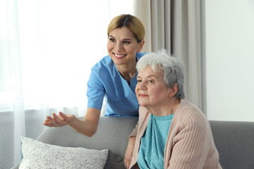 Nurse with elderly woman indoors. Assisting senior people