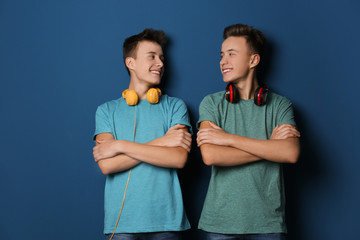 Teenage twin brothers with headphones on color background - obrazy, fototapety, plakaty
