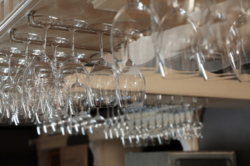 Set of empty clean glasses on bar racks