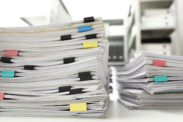 Stacks of documents with paper clips on office desk, closeup