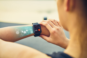 Young woman checking the sports watch with screen healthcare icon,  measuring heart rate and...