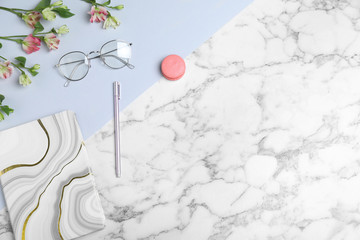 Flat lay composition with notebook, glasses and macaron on marble table, space for text