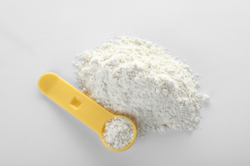 Spoon and pile of protein powder on white background, top view