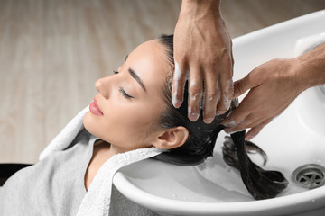 Stylist washing client's hair at sink in beauty salon