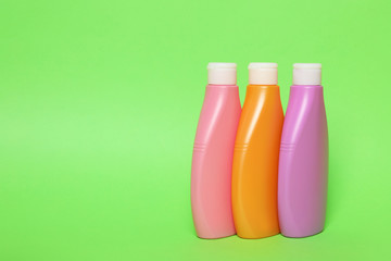 Bottles of shampoo on green background, space for text. Natural cosmetic products