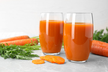 Glasses of drink and carrots on light table, space for text