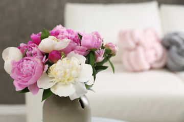 Vase with bouquet of beautiful peonies in room, space for text