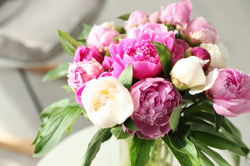 Vase with bouquet of beautiful peonies on table in room, closeup