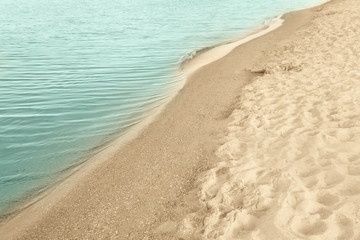 Fototapeta na wymiar View of sea water and beach sand on sunny summer day