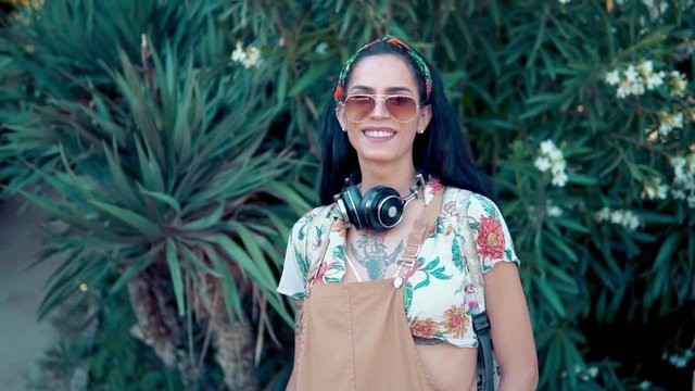 transgender model wearing sunglasses in the green park. She has headphones