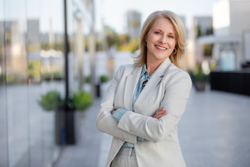 Happy company leader CEO female boss executive standing in front of company building