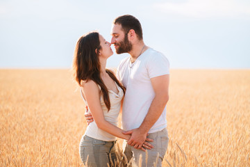 Beautiful couple in love dating outdoors. Young man and woman hugging and kissing standing in the field. Human relationships, love, romance and marriage concept