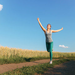 Happy woman on sunset or sunrise. Female runner raising arms expressing positivity and success. Winner, happiness concept