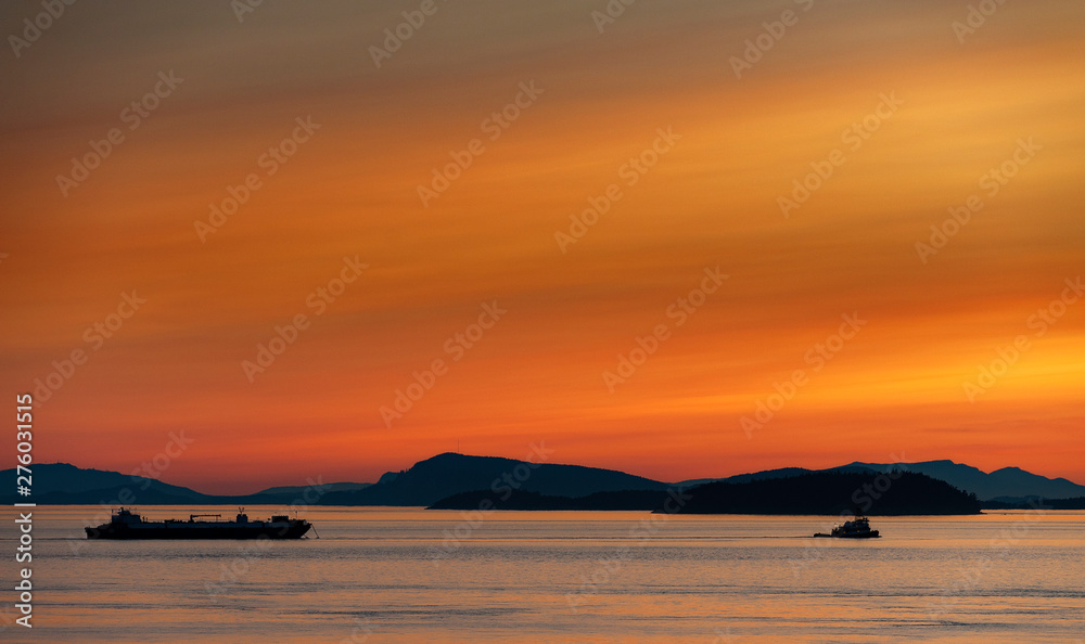 Wall mural tugboat and barge motoring through the puget sound.. with the islands matia and sucia in the backgro