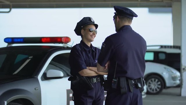 Male and female police officers giving high five communicating on parking lot