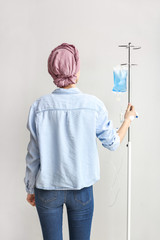 Young woman undergoing chemical therapy course against light background, back view