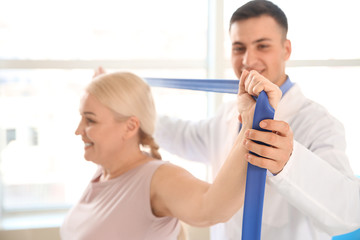 Fototapeta premium Physiotherapist working with mature patient in rehabilitation center