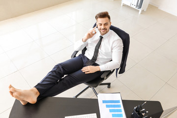 Carefree businessman talking by mobile phone in office