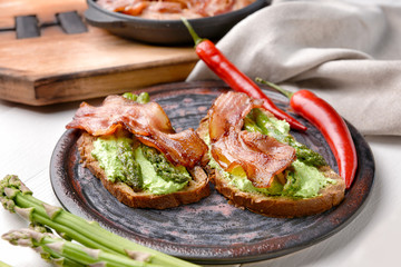 Tasty toasts with bacon on plate