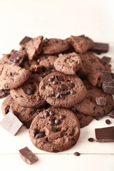 Heap of tasty chocolate cookies on light wooden table