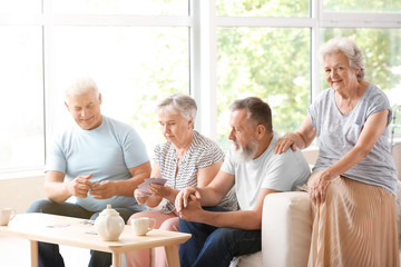 Portrait of elderly people playing cards in nursing home