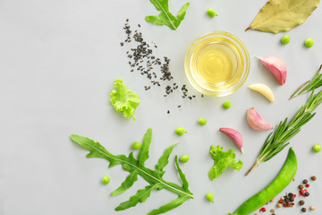 Fresh herbs with vegetables, oil and spices on grey background