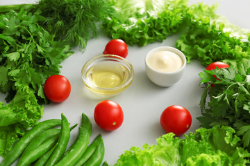Fresh herbs with vegetables, oil and sauce on grey background