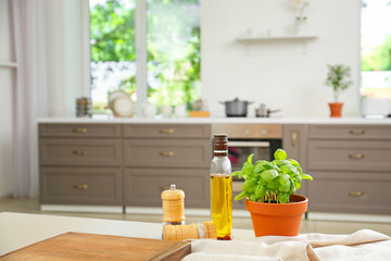 Fresh basil in pot with oil and spices on table in kitchen