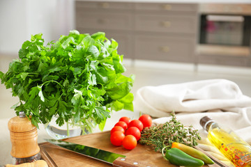 Fresh herbs with vegetables, spices and oil on table in kitchen