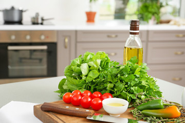 Fresh herbs with vegetables and oil on table in kitchen