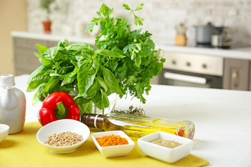 Fresh herbs with spices and oil on table in kitchen
