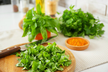 Fototapeta na wymiar Cutting board with knife and fresh herbs on table in kitchen
